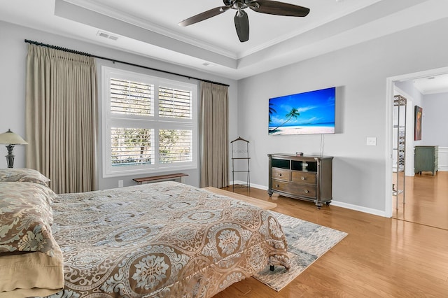 bedroom featuring ceiling fan, hardwood / wood-style flooring, a tray ceiling, and ornamental molding