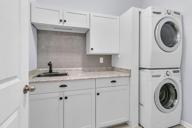 washroom with cabinets, sink, and stacked washer / dryer