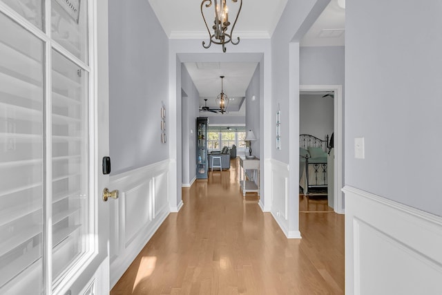 entryway featuring light hardwood / wood-style floors, crown molding, and a notable chandelier