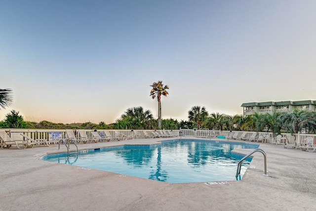 pool at dusk with a patio area