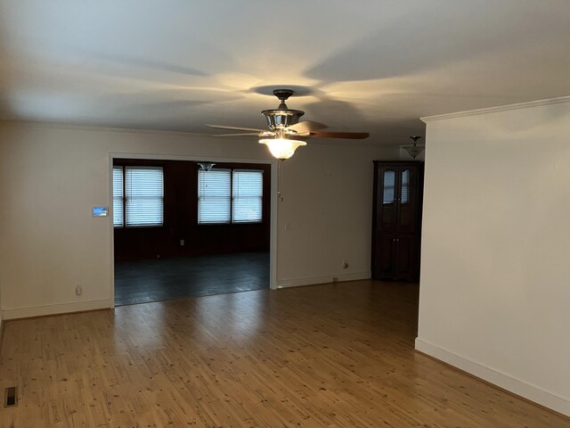 unfurnished room featuring crown molding, ceiling fan, and dark wood-type flooring