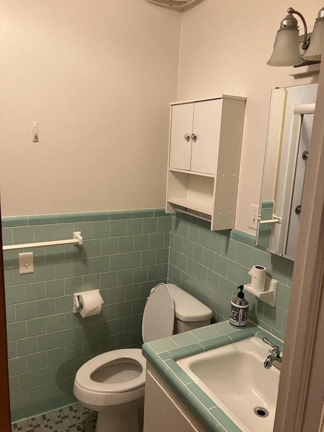 bathroom featuring tile patterned flooring, vanity, toilet, and tile walls