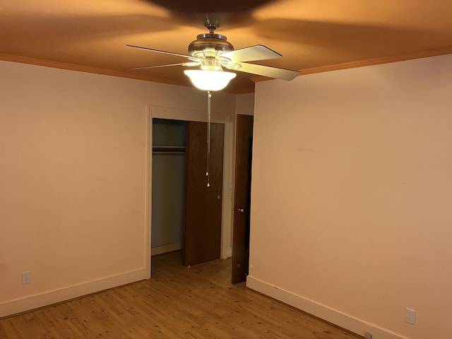 unfurnished bedroom featuring ceiling fan, a closet, ornamental molding, and light hardwood / wood-style flooring