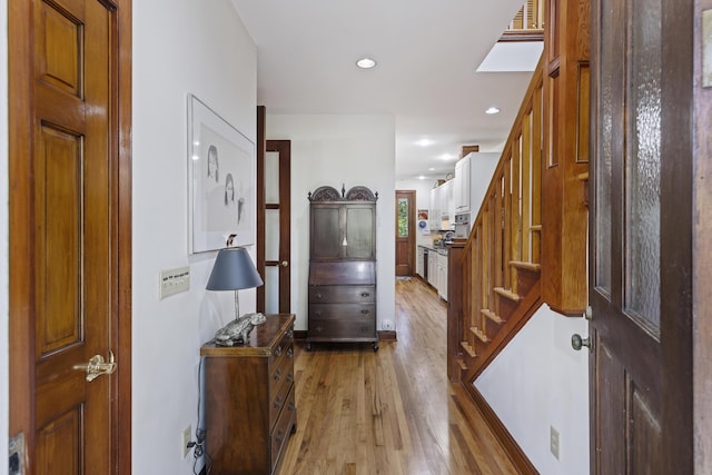 hall with recessed lighting, stairs, and light wood finished floors
