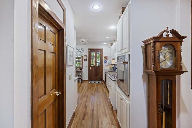 hallway featuring light wood-style flooring, recessed lighting, and baseboards