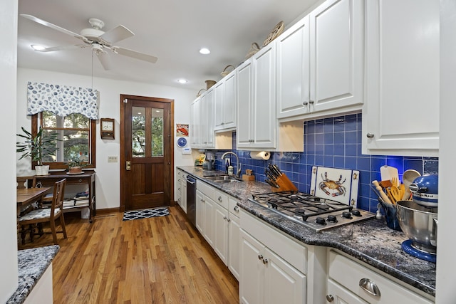 kitchen featuring a sink, ceiling fan, light wood-style floors, white cabinetry, and decorative backsplash