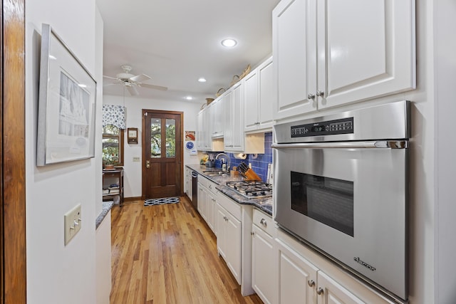 kitchen featuring appliances with stainless steel finishes, a sink, a ceiling fan, and white cabinets
