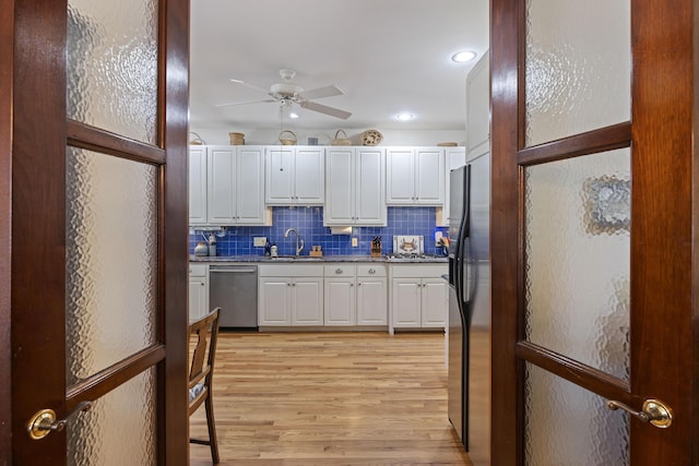 kitchen with stainless steel appliances, light wood-style floors, white cabinetry, and a ceiling fan