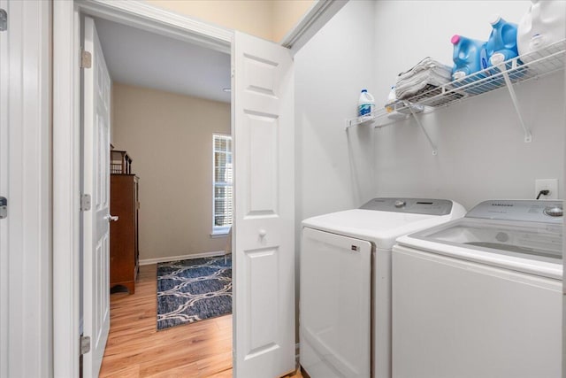 laundry area with washing machine and clothes dryer and light wood-type flooring