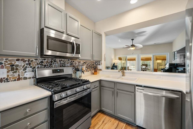 kitchen with stainless steel appliances, sink, gray cabinetry, and decorative backsplash