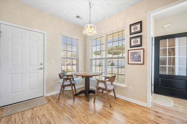 dining room with a wealth of natural light, an inviting chandelier, and light hardwood / wood-style flooring