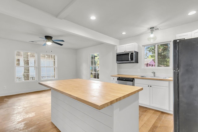 kitchen featuring appliances with stainless steel finishes, wooden counters, white cabinetry, sink, and beam ceiling