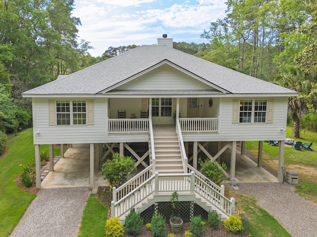 8346 Chisolm Plantation Rd, Edisto Island, SC 29438 - raised beach house featuring a carport, gravel driveway, roof with shingles, and covered porch