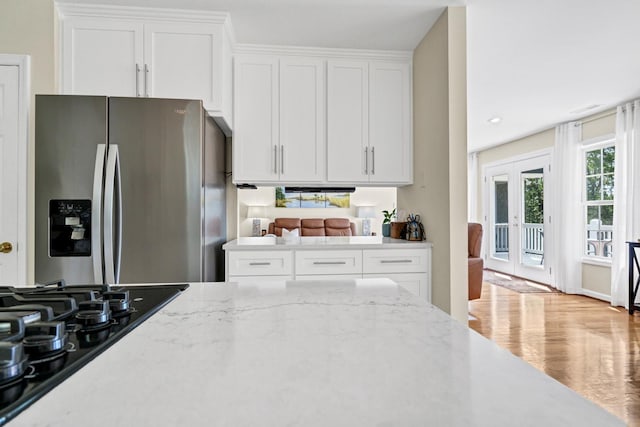 8346 Chisolm Plantation Rd, Edisto Island, SC 29438 - kitchen featuring stainless steel fridge with ice dispenser, black cooktop, white cabinetry, and light stone counters