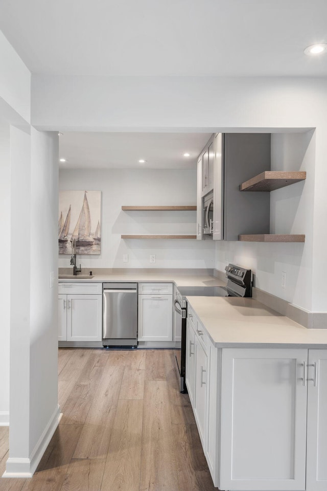 kitchen featuring sink, light hardwood / wood-style flooring, stainless steel appliances, and white cabinets