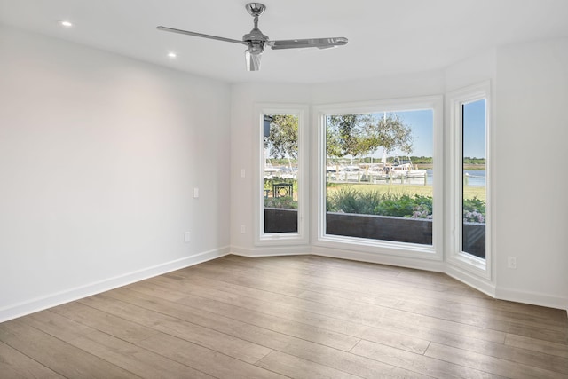 empty room with a water view, ceiling fan, and wood-type flooring