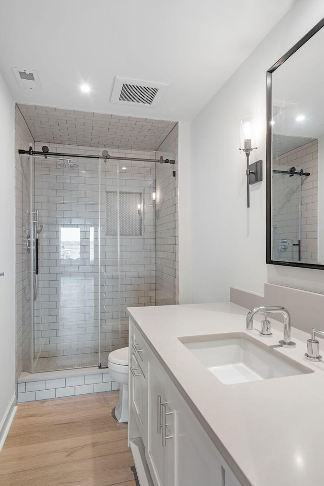 bathroom with vanity, toilet, an enclosed shower, and wood-type flooring