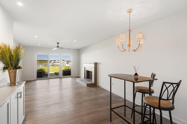 living room with ceiling fan with notable chandelier and dark hardwood / wood-style floors