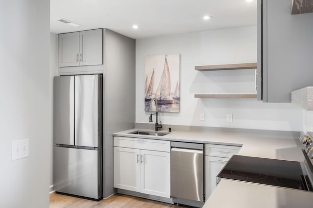 kitchen with gray cabinets, appliances with stainless steel finishes, sink, and light hardwood / wood-style floors