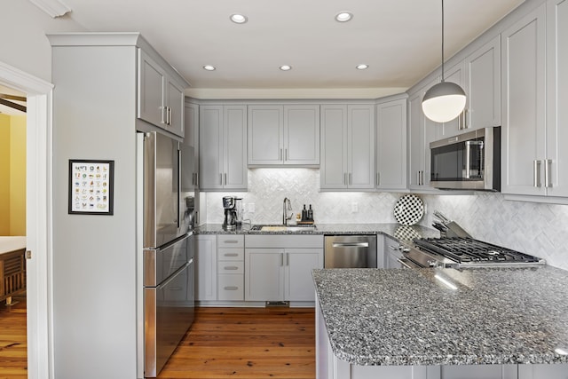 kitchen featuring appliances with stainless steel finishes, sink, pendant lighting, and kitchen peninsula