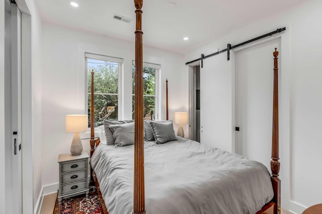 bedroom with hardwood / wood-style flooring and a barn door