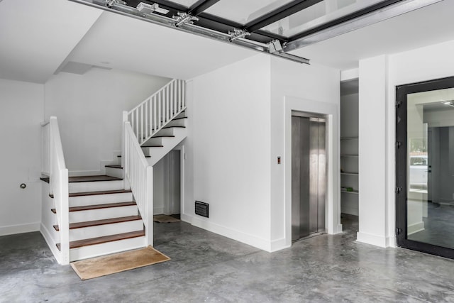 stairs featuring concrete floors and elevator