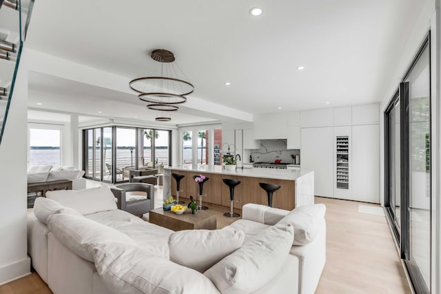 living room with sink, light hardwood / wood-style floors, and a water view