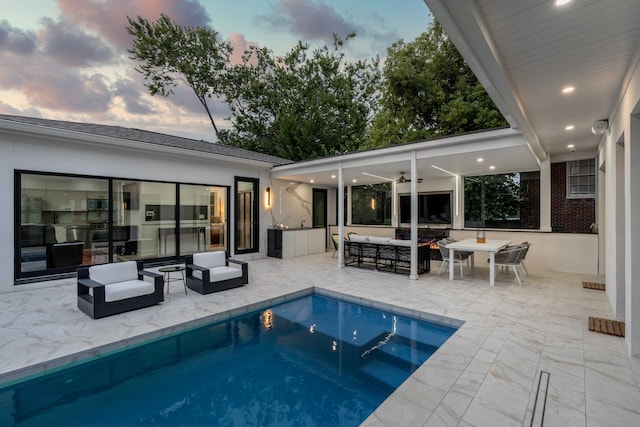 pool at dusk with an outdoor hangout area, a jacuzzi, ceiling fan, and a patio area