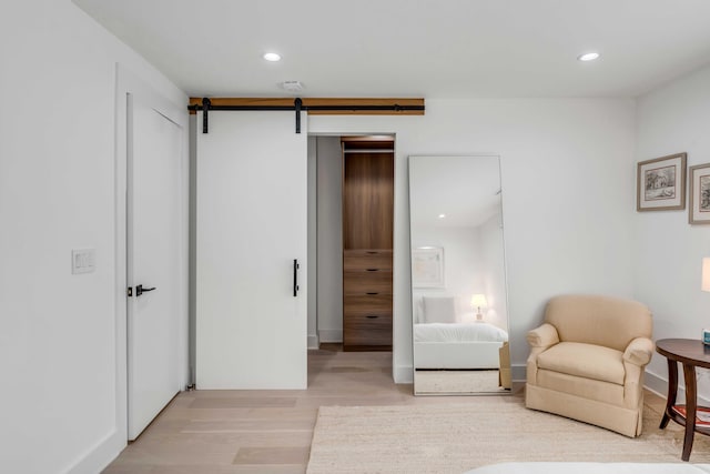 sitting room with a barn door and light wood-type flooring