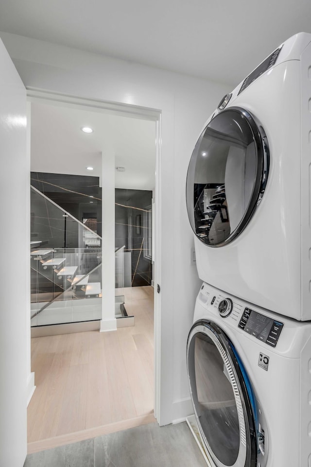 laundry room with hardwood / wood-style flooring and stacked washer and clothes dryer