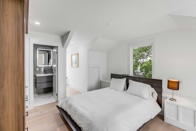 bedroom with lofted ceiling, ensuite bathroom, and light hardwood / wood-style flooring