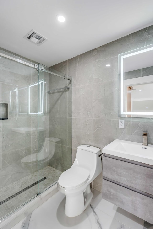 bathroom featuring vanity, toilet, a shower with shower door, and tile walls