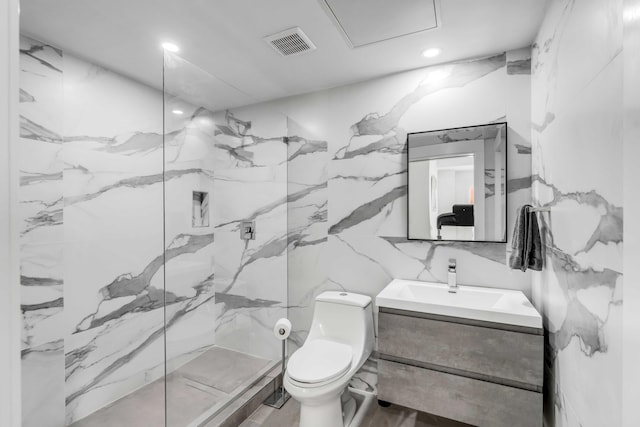 bathroom featuring a tile shower, vanity, tile walls, and toilet