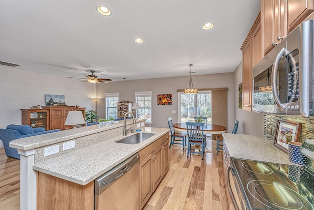 kitchen featuring sink, light hardwood / wood-style floors, pendant lighting, a center island with sink, and appliances with stainless steel finishes