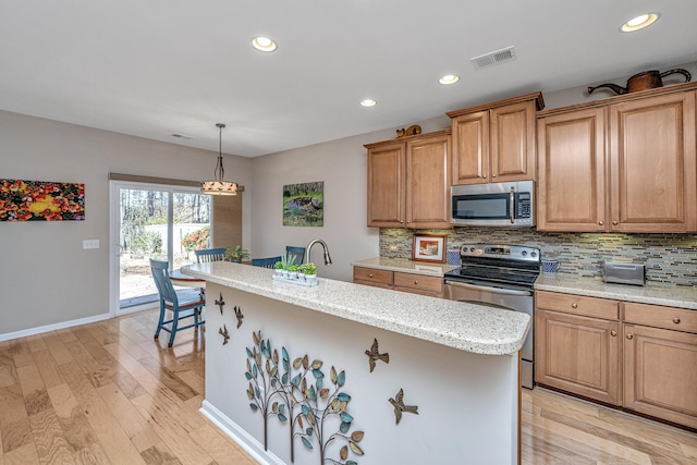 kitchen with backsplash, stainless steel appliances, decorative light fixtures, light hardwood / wood-style flooring, and a center island