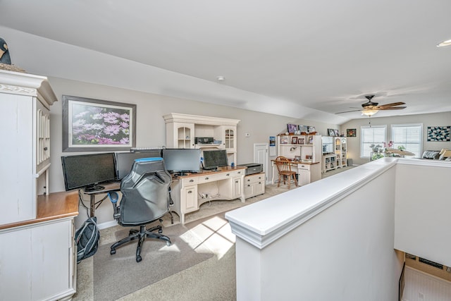 office space featuring light carpet, ceiling fan, and vaulted ceiling