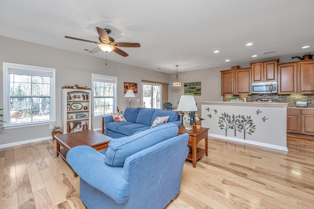 living room featuring ceiling fan and light hardwood / wood-style flooring