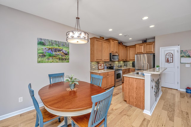 kitchen with sink, tasteful backsplash, pendant lighting, a center island with sink, and appliances with stainless steel finishes