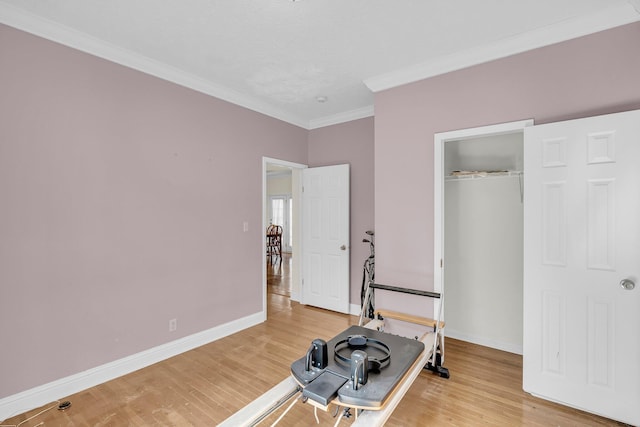 exercise room featuring crown molding and wood-type flooring