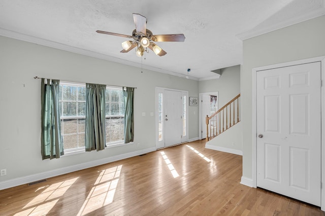 foyer with ceiling fan, ornamental molding, light hardwood / wood-style floors, and a textured ceiling