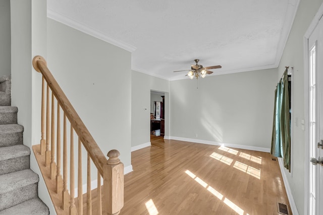 interior space featuring ceiling fan, ornamental molding, light hardwood / wood-style floors, and a textured ceiling