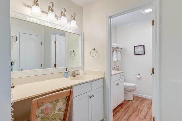 bathroom featuring crown molding, baseboards, toilet, wood finished floors, and vanity