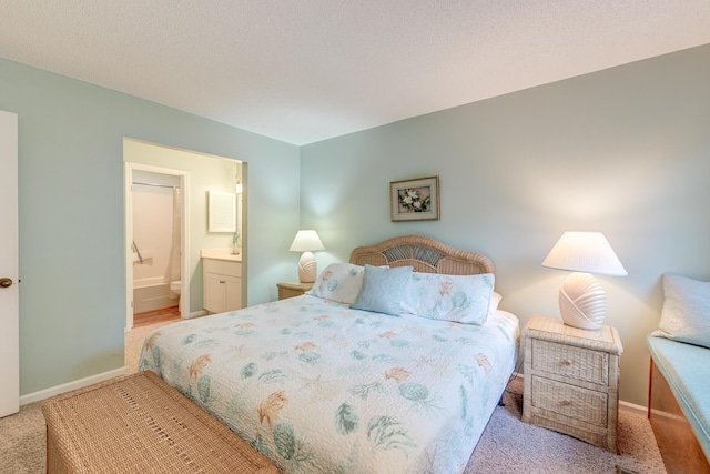 bedroom featuring baseboards, a textured ceiling, and ensuite bathroom