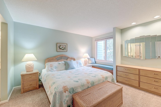 bedroom featuring a textured ceiling, recessed lighting, baseboards, and light carpet