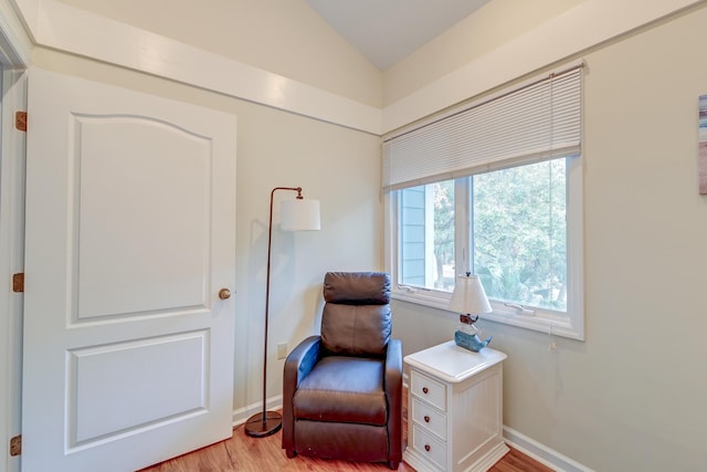 living area with light wood-style flooring, baseboards, and lofted ceiling