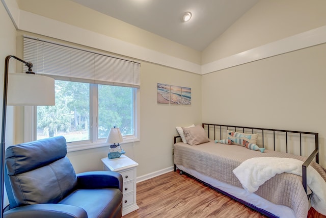 bedroom with baseboards, lofted ceiling, and light wood finished floors