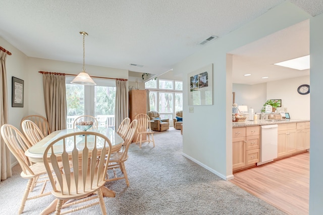 dining room with light carpet, visible vents, a textured ceiling, and baseboards