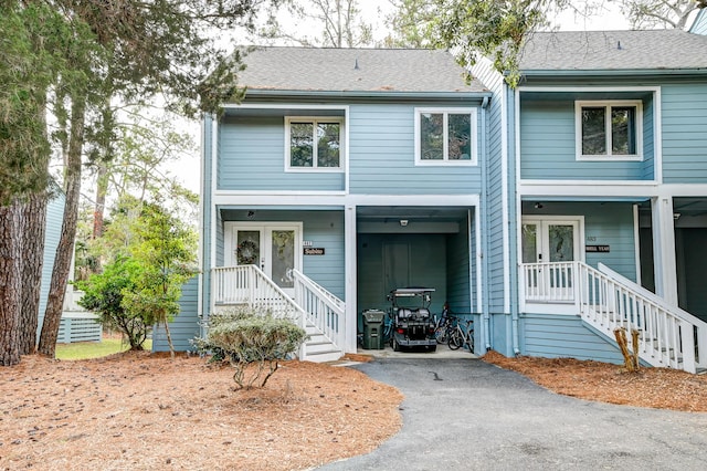 view of front of home with french doors, roof with shingles, and driveway