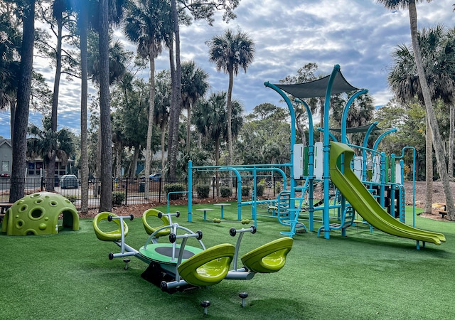 communal playground featuring a yard and fence