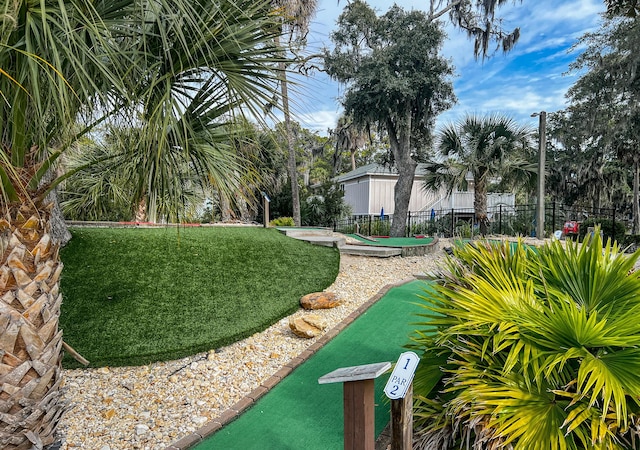 view of property's community featuring a lawn and fence